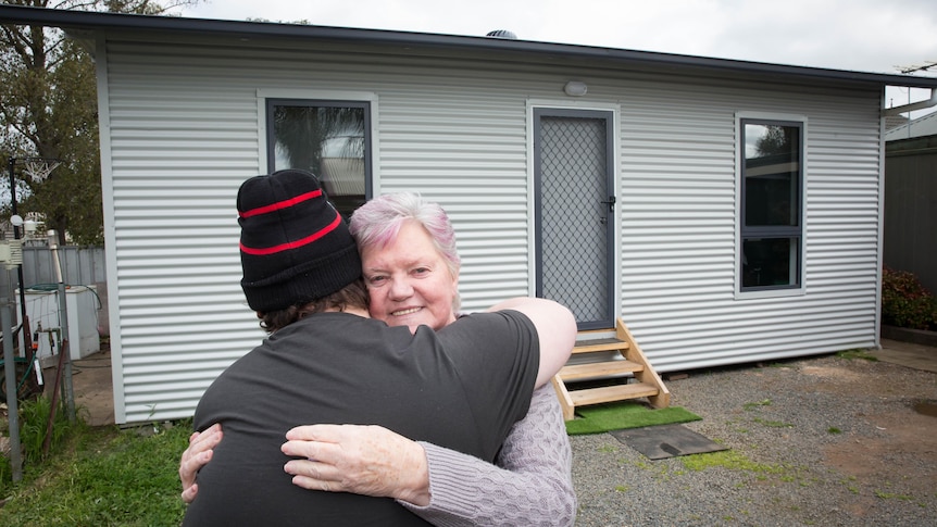 A great grandmother hugging her son outside a studio