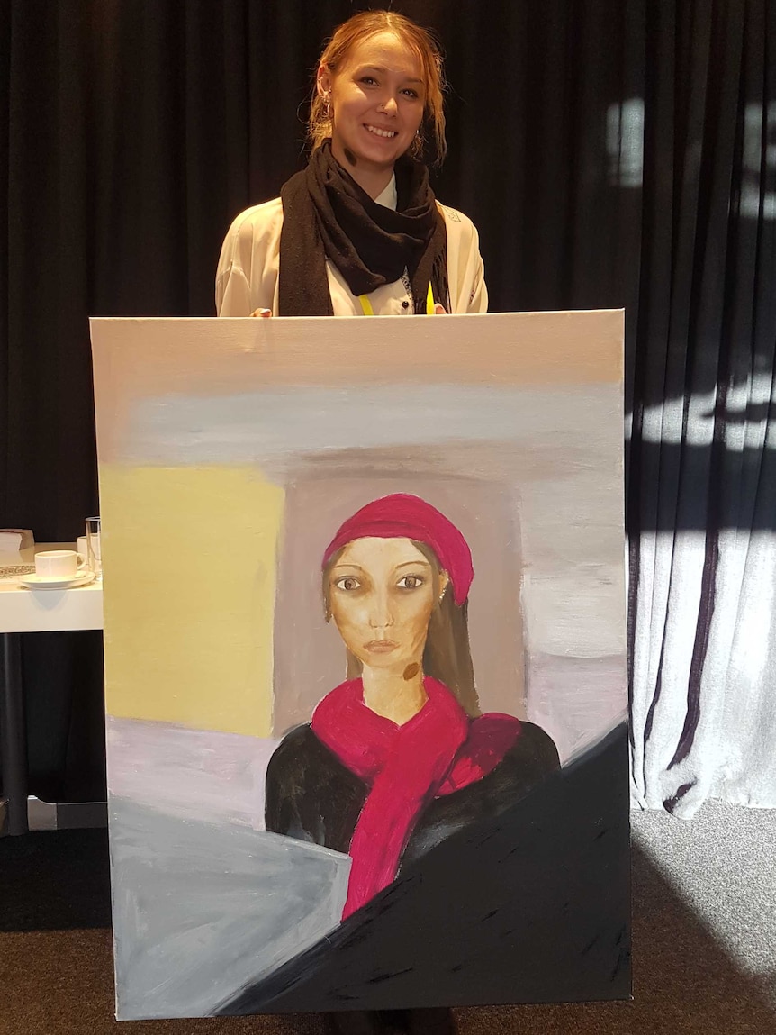 A woman stands with her painting