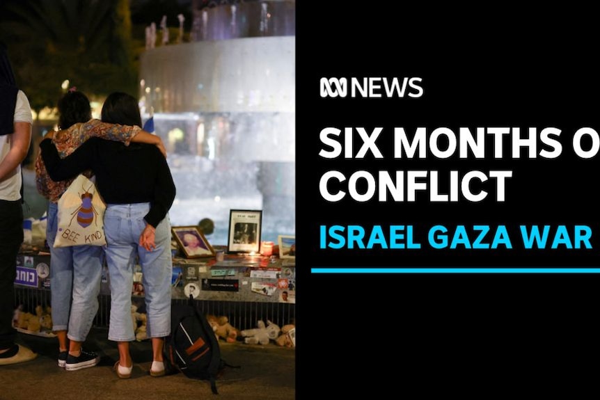 Six Months Of Conflict, Israel Gaza War: A man and two women hold each other as they look at vigil of photographs and candles.