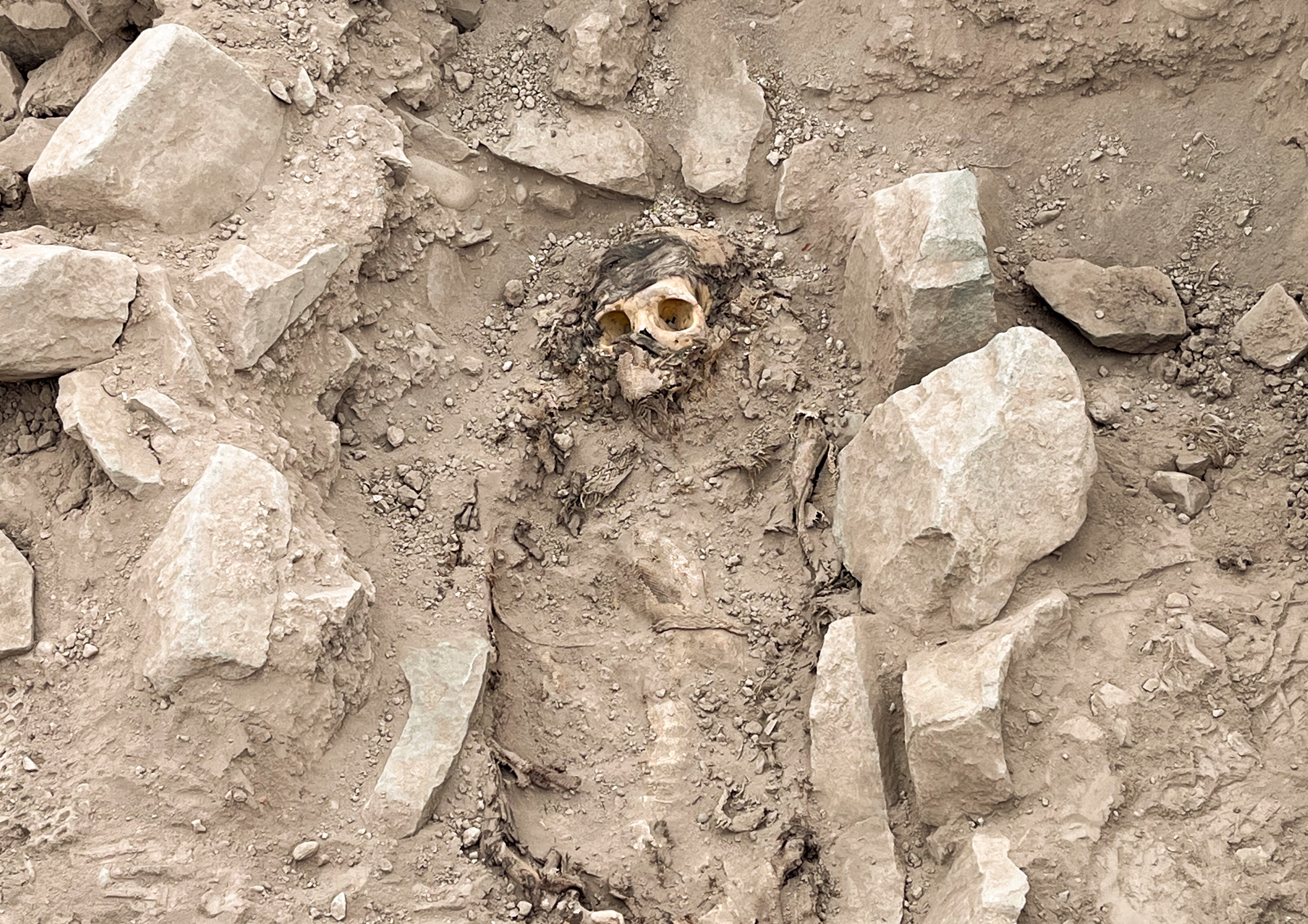 A skull submerged in dirt surrounded by large rocks.