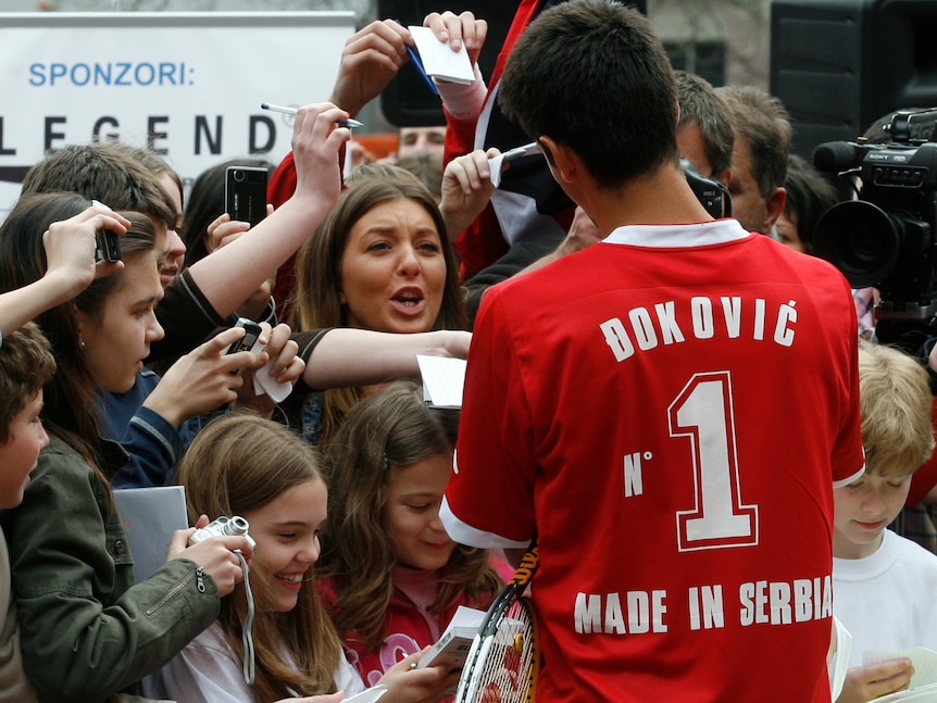 Novak Djokovic signs autographs at an exhibition tennis match.