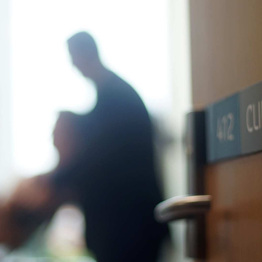 Blurred image of a doctor with a patient at the Curtin Medical School with a door marked "clinical skills" in the foreground.