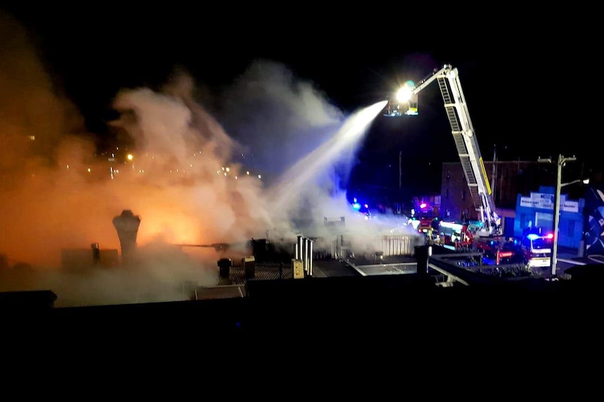 An aerial firefighting unit sprays water onto flames above a Newcastle West bar at night.