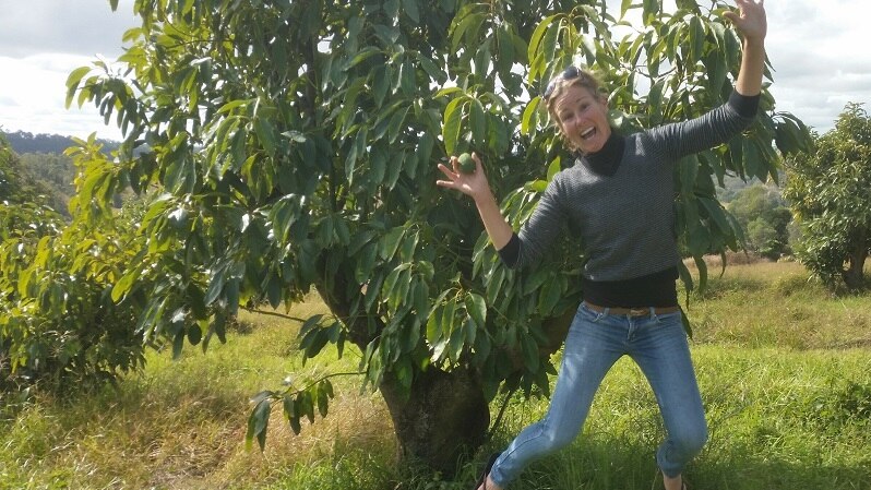 Kate Groves jumping for joy on her avocado farm.