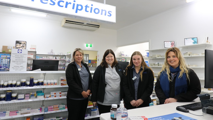Tumby Bay Pharmacy workers standing alongside each other behind the counter in front of medicines.