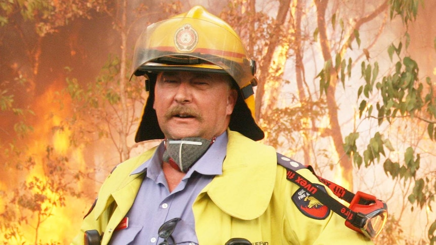 Mr Campion in firefighting outfit in front of bushfire