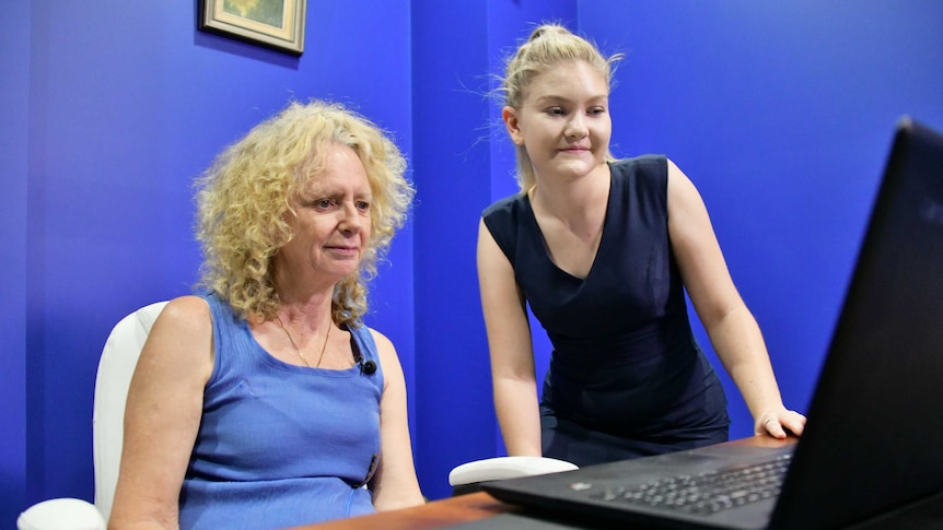 Woman showing another woman how to use the computer system