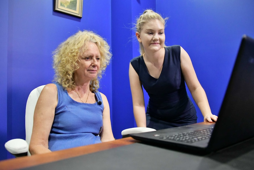 Woman showing another woman how to use the computer system