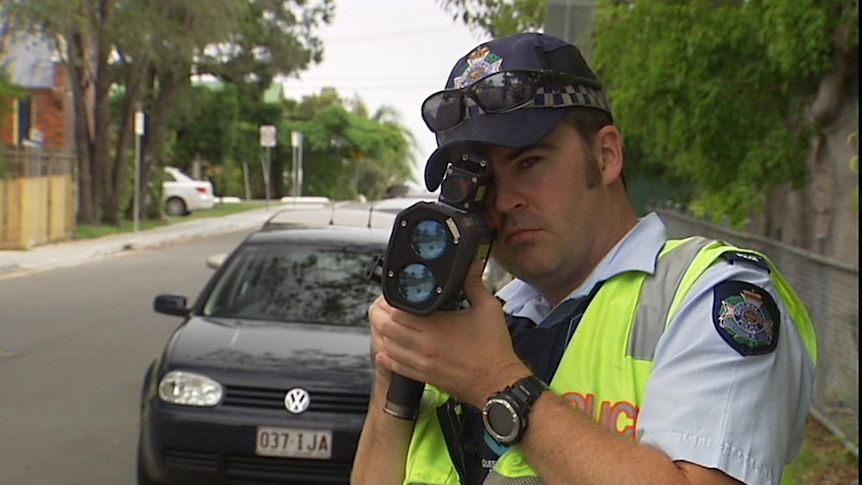 A policeman points a Llidar speed gun.