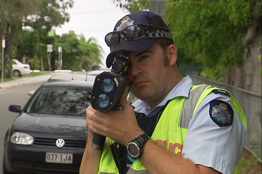 A policeman points a Llidar speed gun.