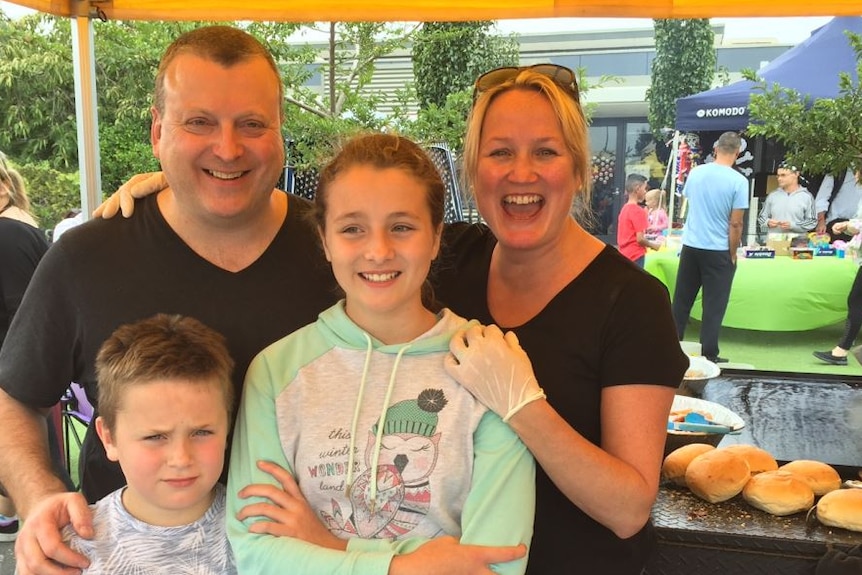 Family smiles in a photo at a bbq