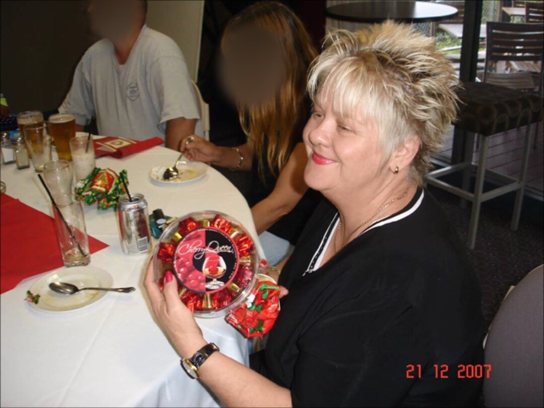 A smiling lady unwraps a present.