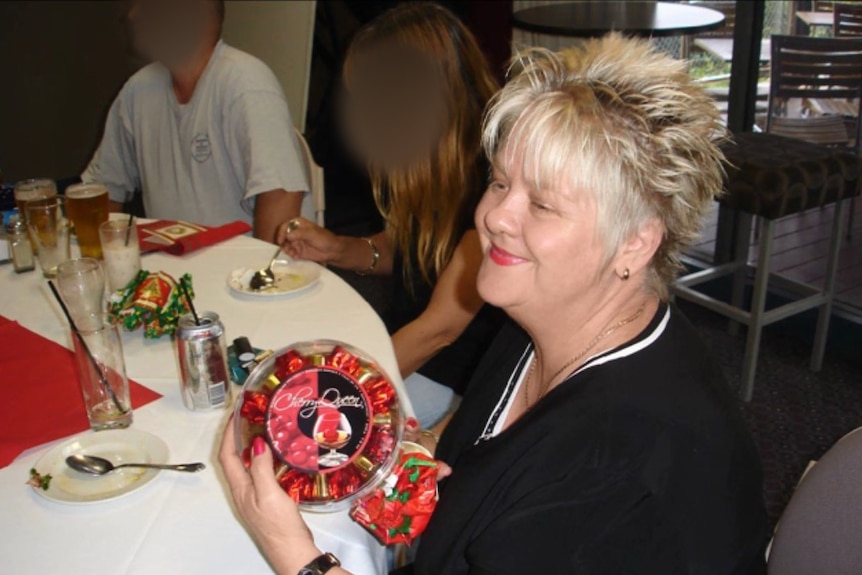 A smiling lady unwraps a present.