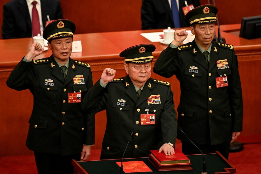 三名军人举起右拳宣誓就职。