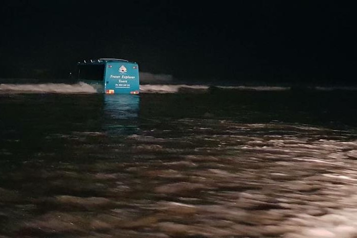 A bus bogged on a Fraser Island beach at night.