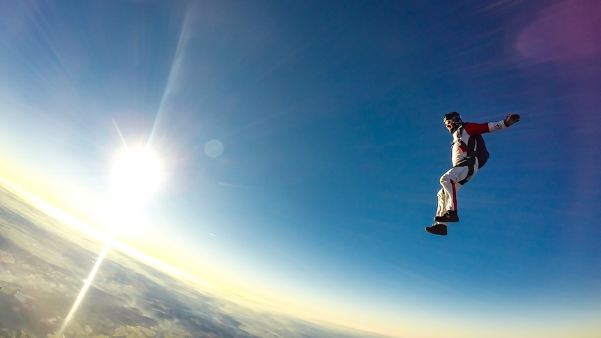 A man falling in the sky before his parachute opens.