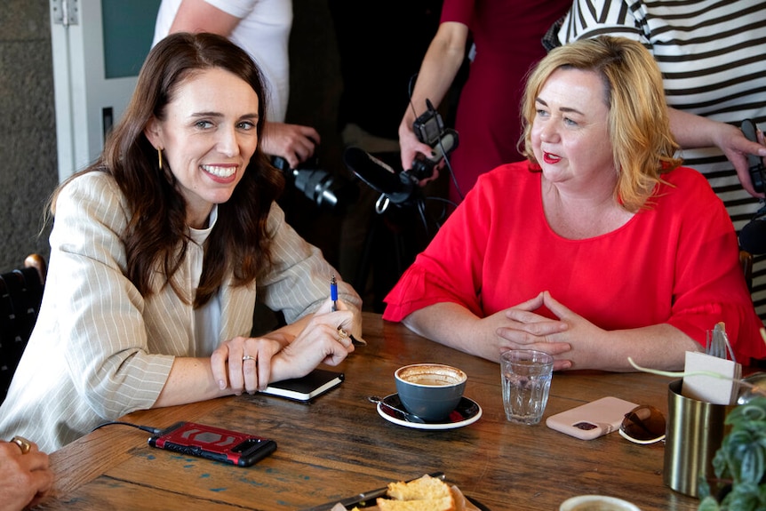 New Zealand Prime Minister Jacinda Ardern, left, and Megan Woods talk with colleagues at a cafe in Auckland, New Zealand.