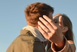 A woman's outstretched hand with an engagement ring on it.