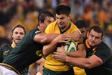 Jack Maddocks is tackled by two Springboks while making a run