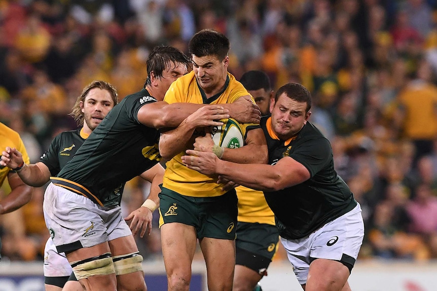 Jack Maddocks is tackled by two Springboks while making a run