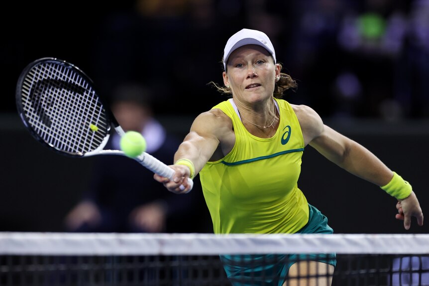 Australian tennis player Samantha Stosur lunges to her right to hit a forehand at the net during a match.