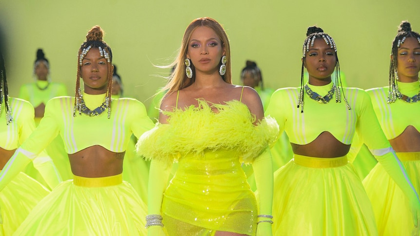 Beyoncé in a yellow costume, onstage with backup dancers