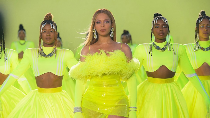 Beyoncé in a yellow costume, onstage with backup dancers