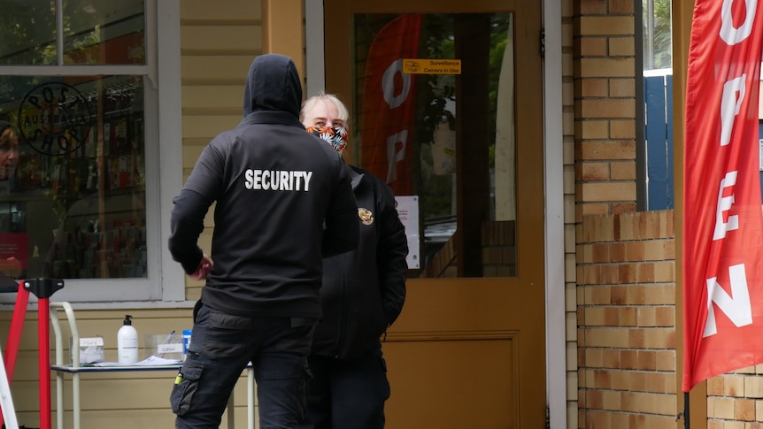 two security officers standing outside byron bay post office shop