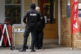 two security officers standing outside byron bay post office shop