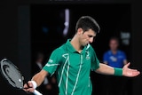 A tennis player spreads his arms wide after losing a point.
