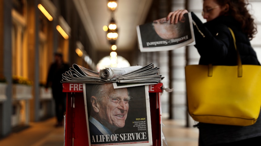 A woman picks up a newspaper with a tribute to Britain's Prince Philip on the front page at Leicester Square.