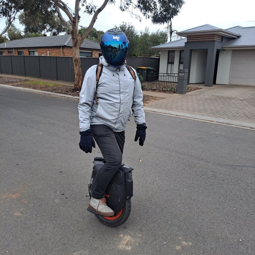 A man riding an electric unicycle on a suburban street