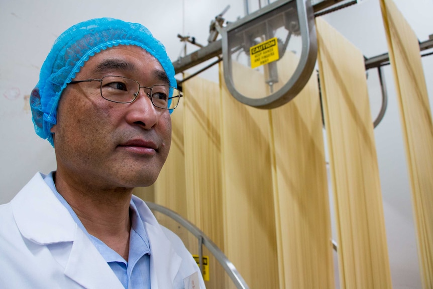 CEO of Hakubaku Australia Ryuji Nakamura stands in front of noodles being processed.