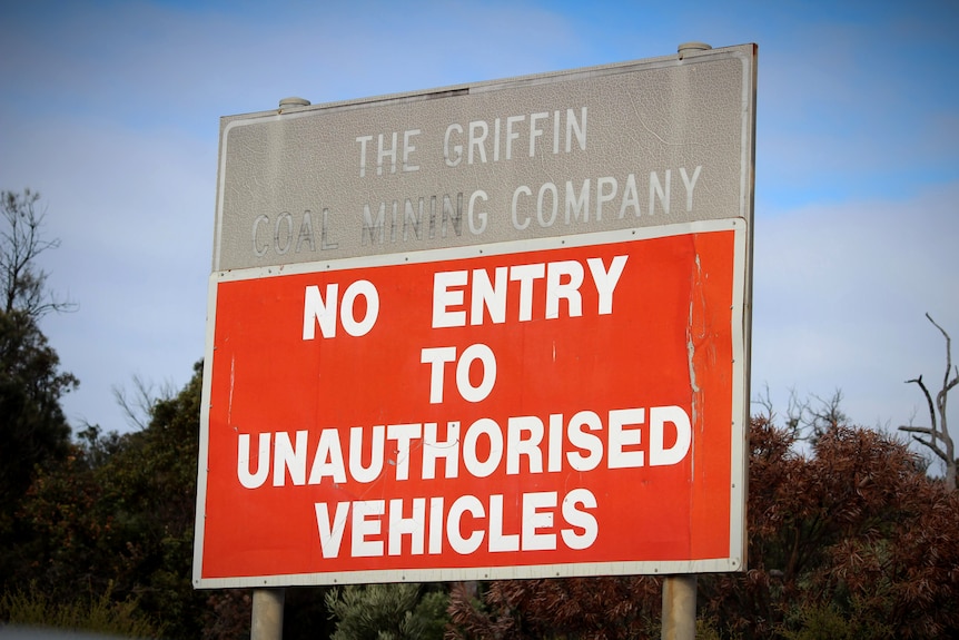 A red and grey sign at the front of a rural property