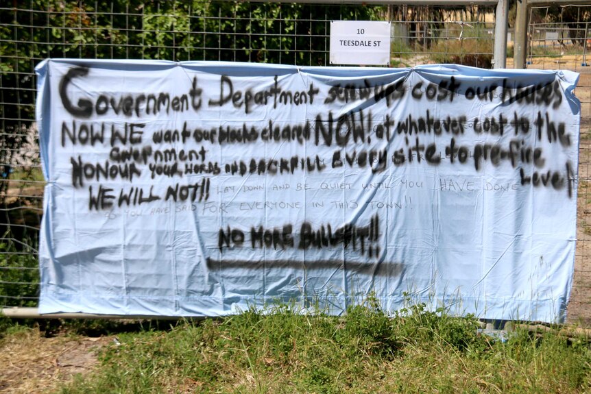 A bed sheet spray painted with a sign angry at the government.