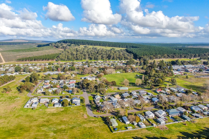 Aerial photo of a small sized town surrounded by paddocks and forests.