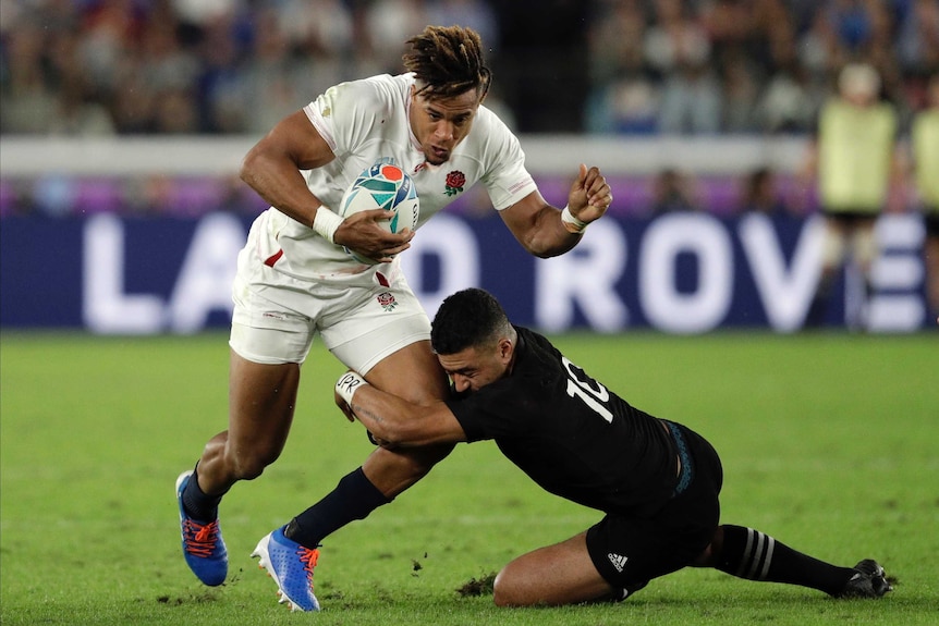 An England rugby union player stands in a tackle from a New Zealand opponent in their Rugby World Cup semi-final.