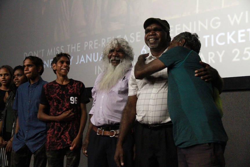 Six members of the Sweet Country cast smiling in front of the cinema screen in Alice Springs
