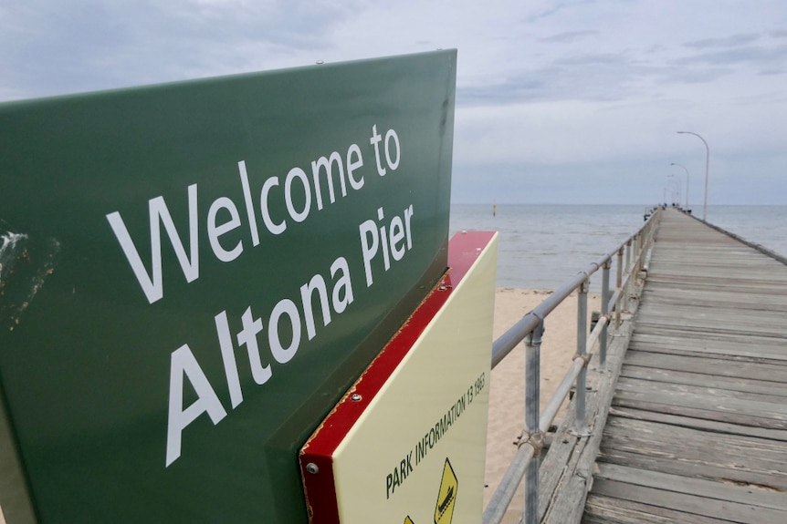 A sign beside a wooden pier reads 'welcome to Altona Pier'.