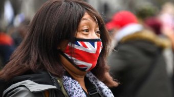 A woman wears a face mask with the UK flag printed on