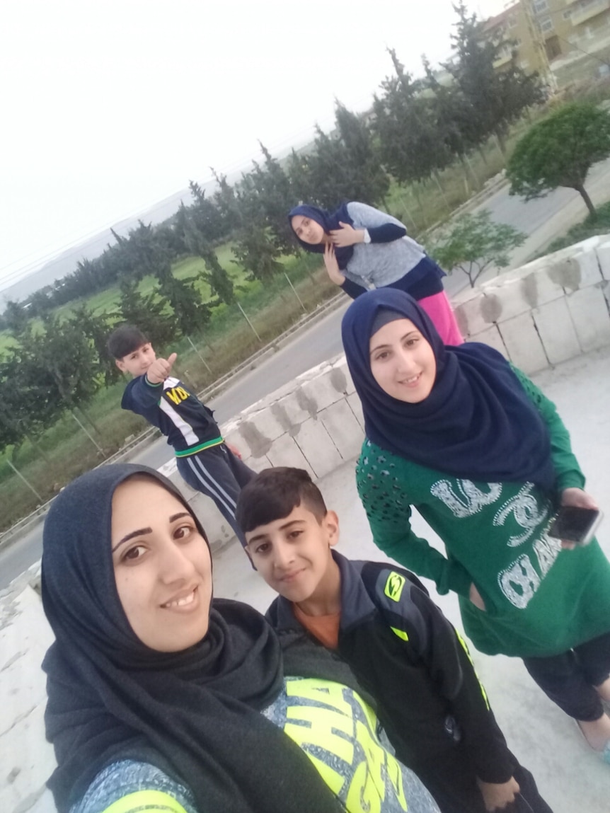 The Zalghanah family pose for a selfie with a field in the background.