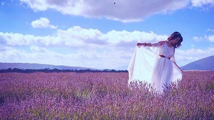 A woman in a floaty white dress stands in a lavender field.