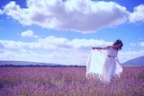 A woman in a floaty white dress stands in a lavender field.