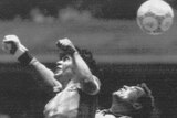 A black and white photo of Diego Maradona leaping towards Peter Shilton. Both have fists up. The ball is now past them