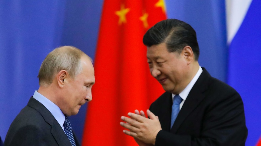 Vladimir Putin (left) looks down as a Xi Jinping smiles at him.