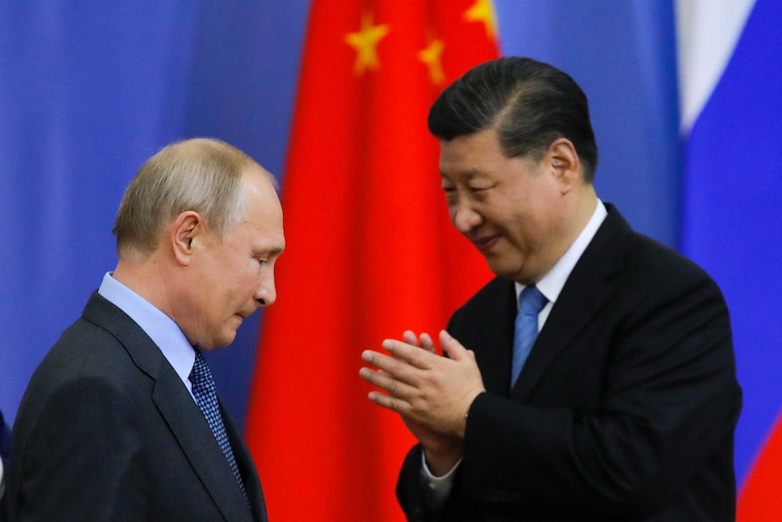 Vladimir Putin (left) looks down as a Xi Jinping smiles at him.