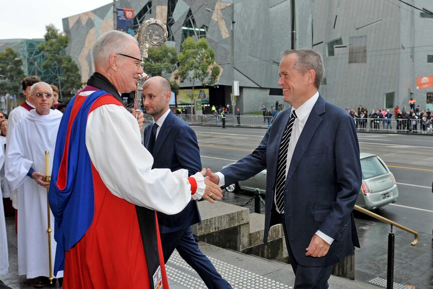 Archbishop Philip Freier shakes the hand of Bill Shorten outside Lou Richards' funeral in Melbourne.
