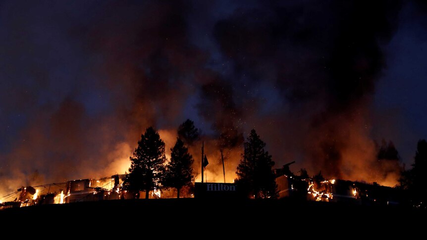 A wide shot shows the Hilton Sonoma burning orange against a night sky.