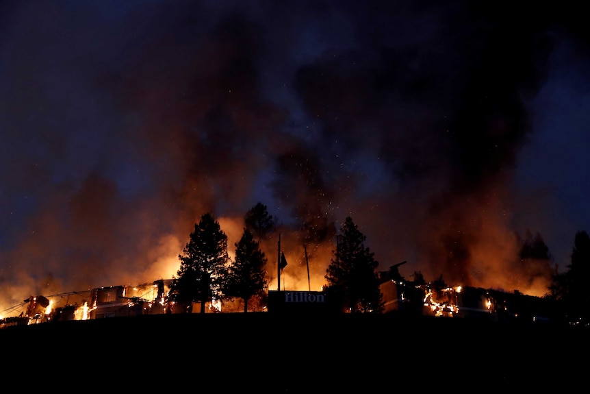 A wide shot shows the Hilton Sonoma burning orange against a night sky.