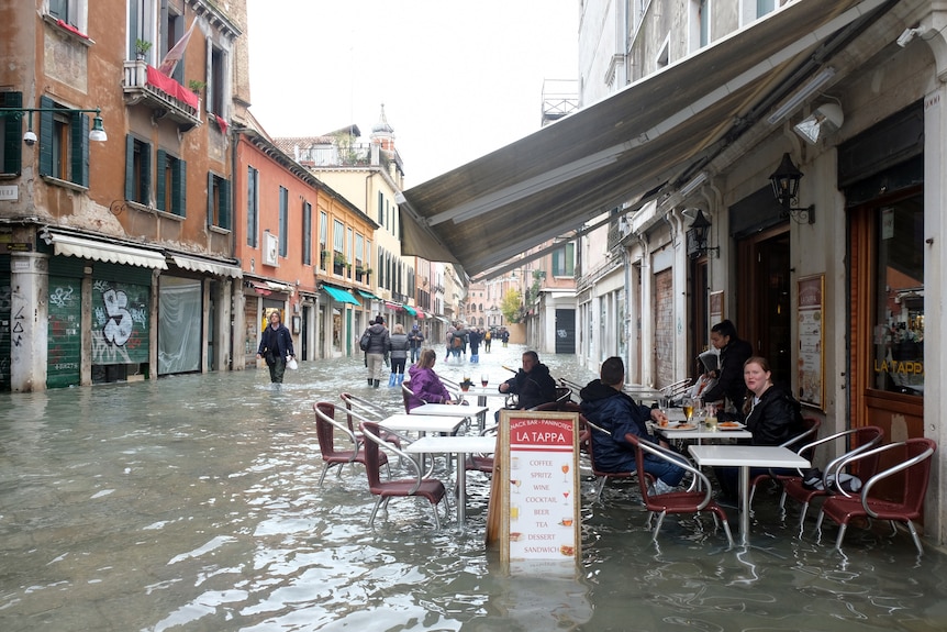 People sit at a cafe in a flooded street